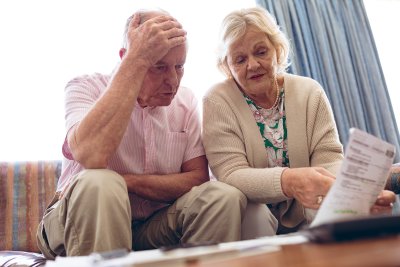 Senior couple sitting on couch looking at bank statement