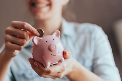 women putting coin in piggy bank
