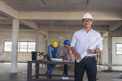 Man holding plans with construction works behind him